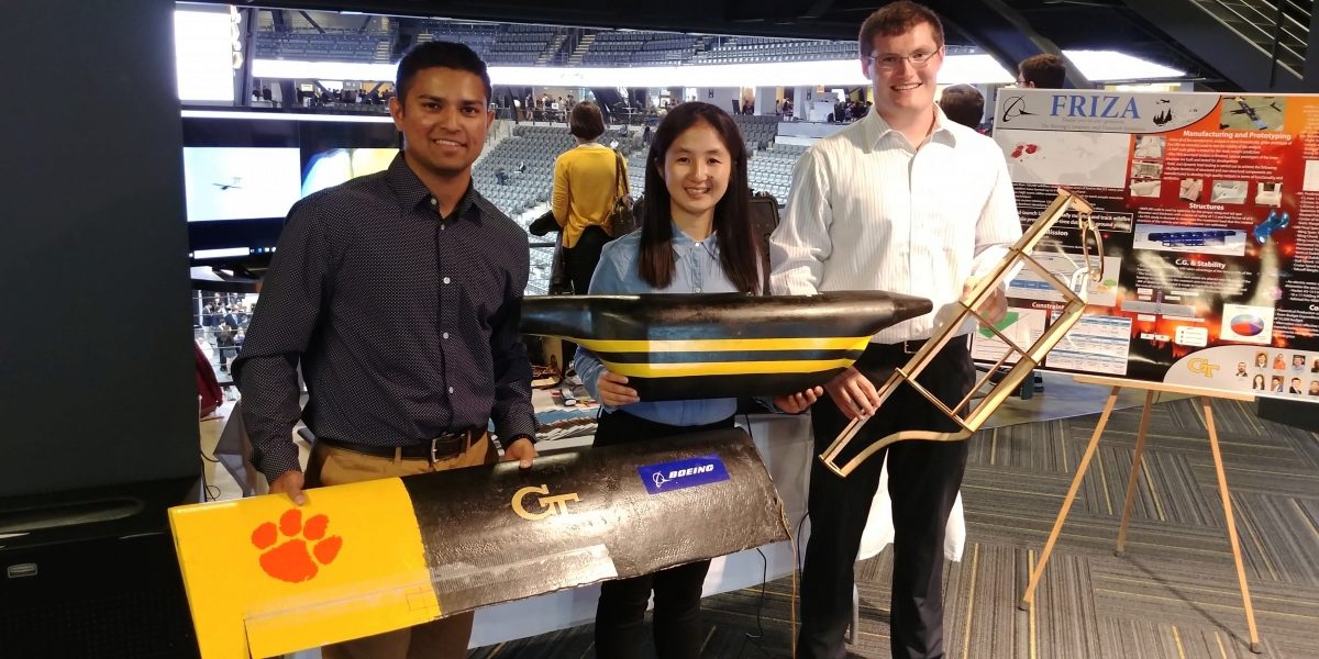 Three members of TEAM FRIZA standing in front of their poster at the Expo