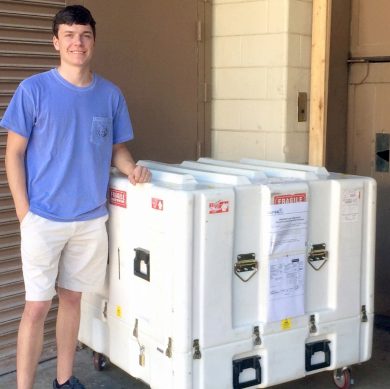 Grayson Huggins standing next to the box that was used to ship Prox 1 off for inspection by the AFRL in 2017